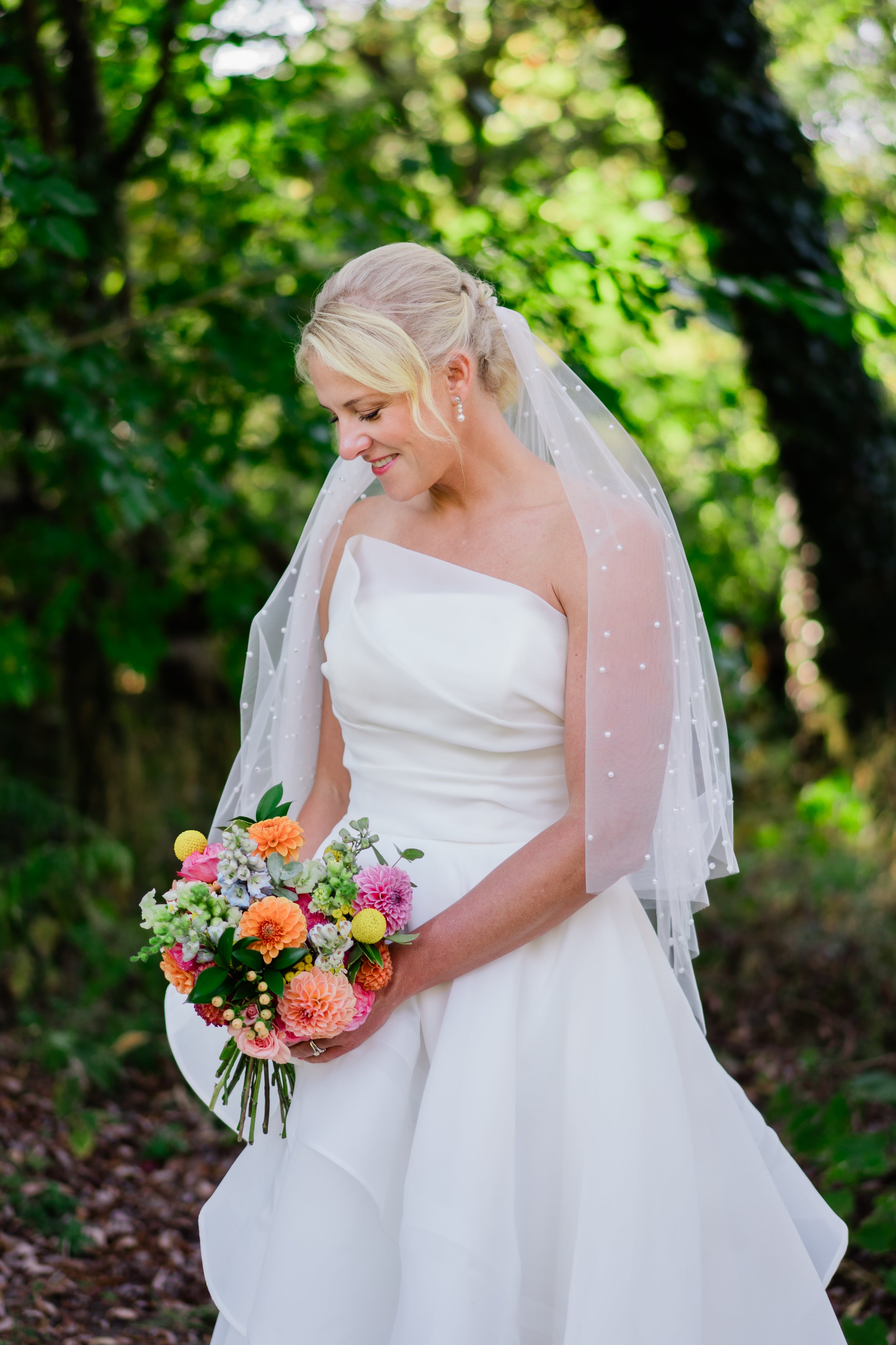 Bride in a white wedding dress holding a bouquet of flowers in a forest setting